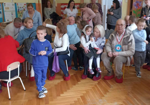 babcie i dziadkowie siedzą ze swoimi wnukami