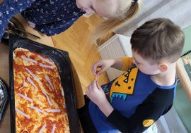 Dzieci układają skłądniki na pizzy