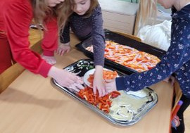 Dzieci układają skłądniki na pizzy