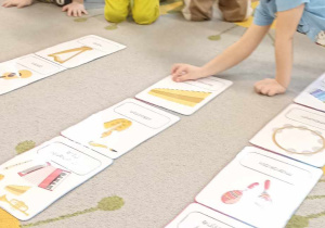 dzieci siedzą na dywanie i układają ilustracje instrumentów