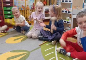 dzieci siedzą na dywanie z instrumentami perkusyjnymi