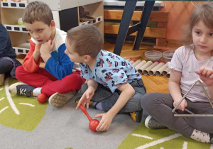dzieci siedzą na dywanie z instrumentami perkusyjnymi