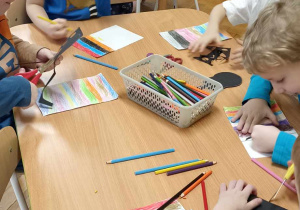 dzieci kolorują kartkę w kolorowe paski