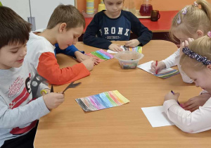 dzieci kolorują kartkę w kolorowe paski
