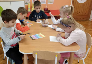 dzieci kolorują kartkę w kolorowe paski