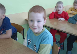 dzieci siedzą w ławkach