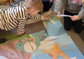 Dzieci układają duże puzzle z dinozaurami