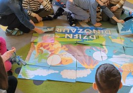 Dzieci układają duże puzzle z dinozaurami