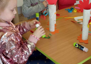 dzieci doklejają elementy z papieru kolorowego do rolki