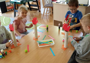 dzieci doklejają elementy z papieru kolorowego do rolki