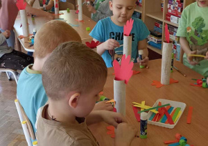 dzieci doklejają elementy z papieru kolorowego do rolki