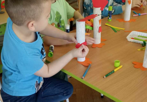 dzieci doklejają elementy z papieru kolorowego do rolki