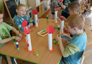 dzieci doklejają elementy z papieru kolorowego do rolki