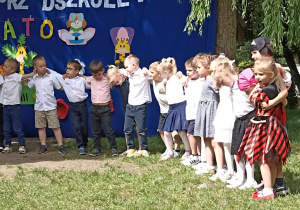 dzieci stoją na trawie w ogródku