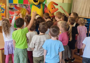 dzieci przytulają się do wielkiej papugi