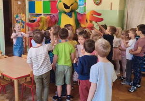 dzieci przytulają się do wielkiej papugi