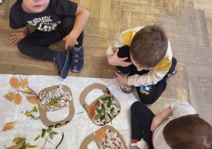 Dzieci wyklejają koszyczek przy pomocy naturalnych materiałów