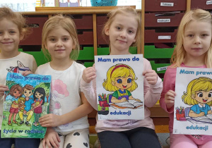 dzieci klęczą trzymając ilustrację