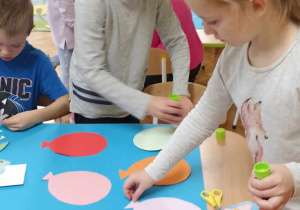dzieci przy stole naklejają kolorowe balony