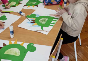 dzieci siedzą przy stole i ozdabiają literę D