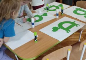 dzieci siedzą przy stole i ozdabiają literę D