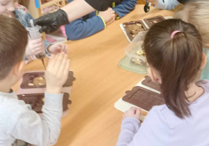 dzieci wciskają ze strzykawki czekoladę do foremek