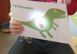 dzieci trzymają ilustrację dinozaura