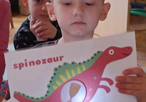 dzieci trzymają ilustrację dinozaura