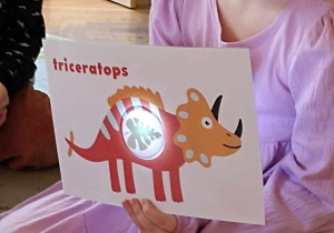 dzieci trzymają ilustrację dinozaura