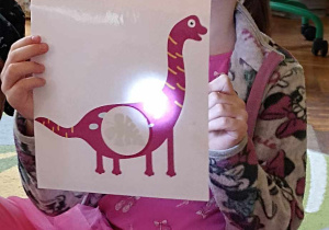 dzieci trzymają ilustrację dinozaura