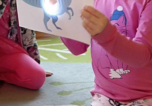dzieci trzymają ilustrację dinozaura