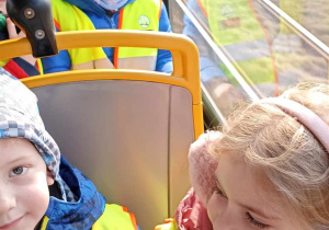 dzieci siedzą w kamizelkach odblaskowych