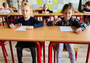dzieci siedzą w ławkach