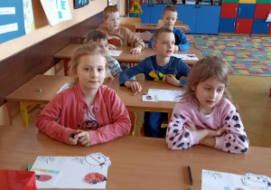 dzieci siedzą w ławce