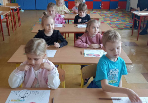 dzieci siedzą w ławce