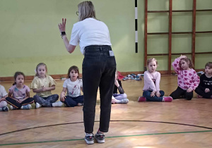 dzieci siedzą na sali gimnastycznej