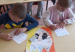 dzieci siedzą w ławce