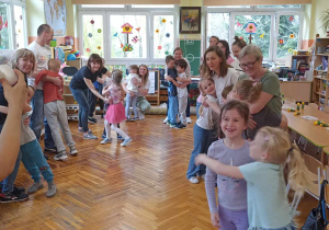 rodzice i dzieci przy stole ozdabiają koszyczek i jajko