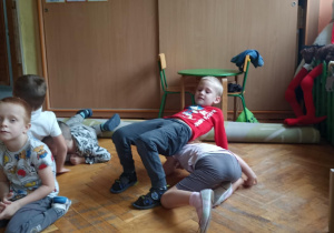 dzieci siedzą na podłodze i ćwiczą