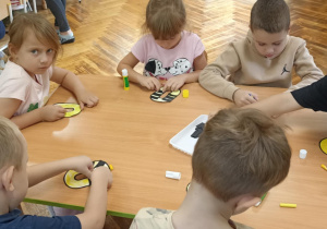 dzieci kolorują literę o i doklejają elementy