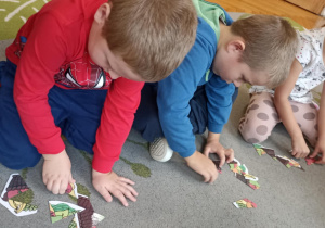 dzieci układają puzzle na dywanie