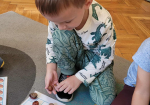 Dzieci układają wzory z kasztanów w lustrzanym odbiciu