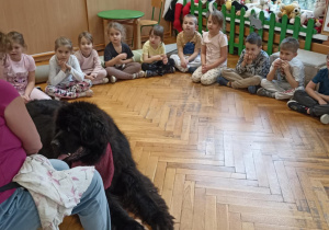 dzieci siedzą w kole przy psie