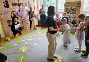 dzieci z rodzicami stoją na dywanie