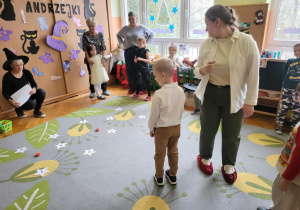 dzieci z rodzicami stoją na dywanie