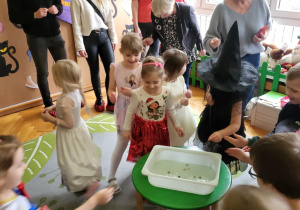 dzieci z rodzicami stoją na dywanie