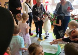 dzieci z rodzicami stoją na dywanie