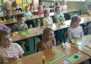 dzieci siedzą w ławkach