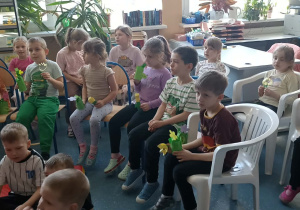 dzieci siedzą na krzesełkach