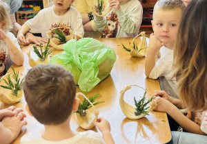 Dzieci z rodzicami wykonują koszyczki wielkanocne